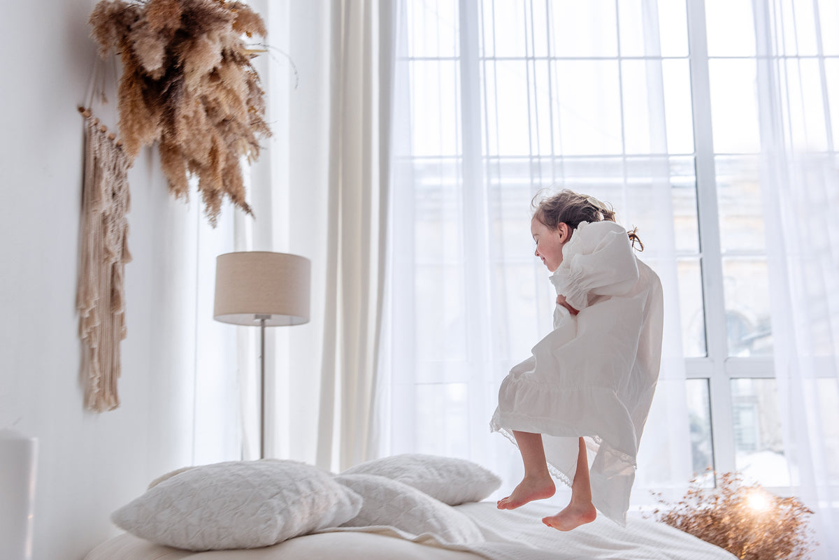 Kind speelt op bed in een licht slaapkamerinterieur; een goede huisstofmijt stofzuiger helpt allergieën voorkomen in kinderkamers